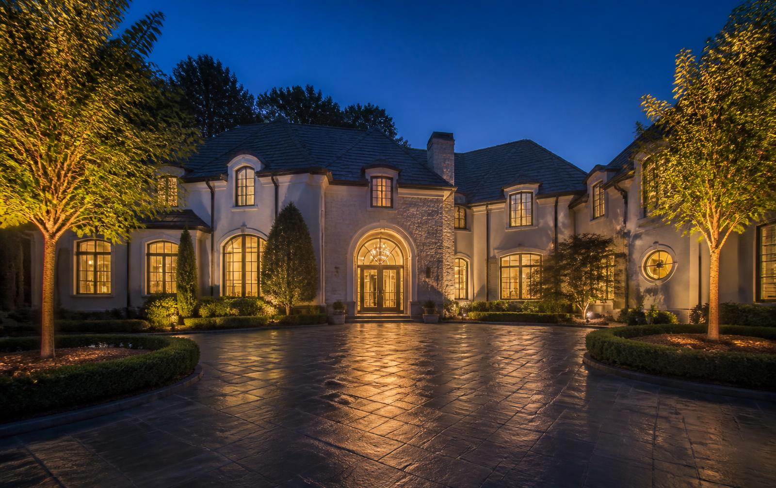 Charlotte luxury home at dusk with lit motor court and glowing windows