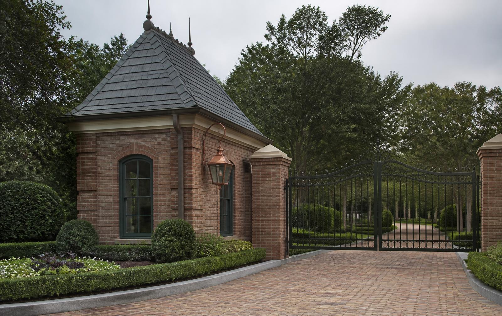 Brick gatehouse with copper lantern and wrought-iron entrance gates to a private drive