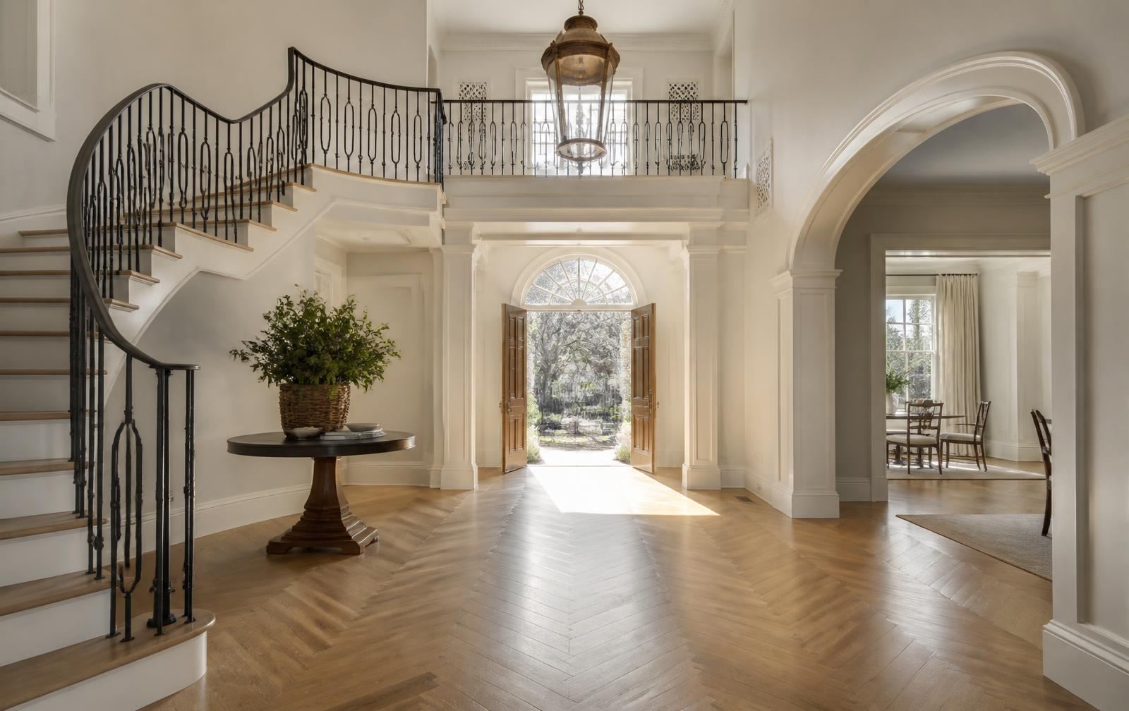 Two-story entry foyer with curved staircase, iron balustrade and herringbone oak floors