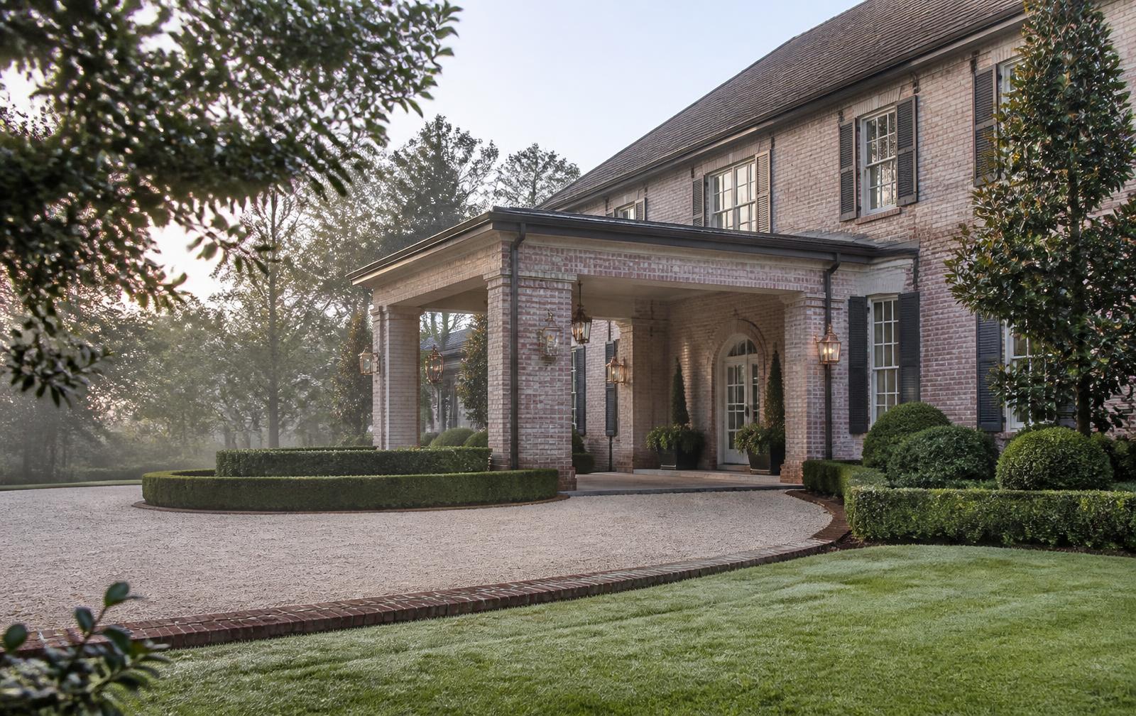 Brick estate porte-cochere and circular gravel motor court on a misty morning