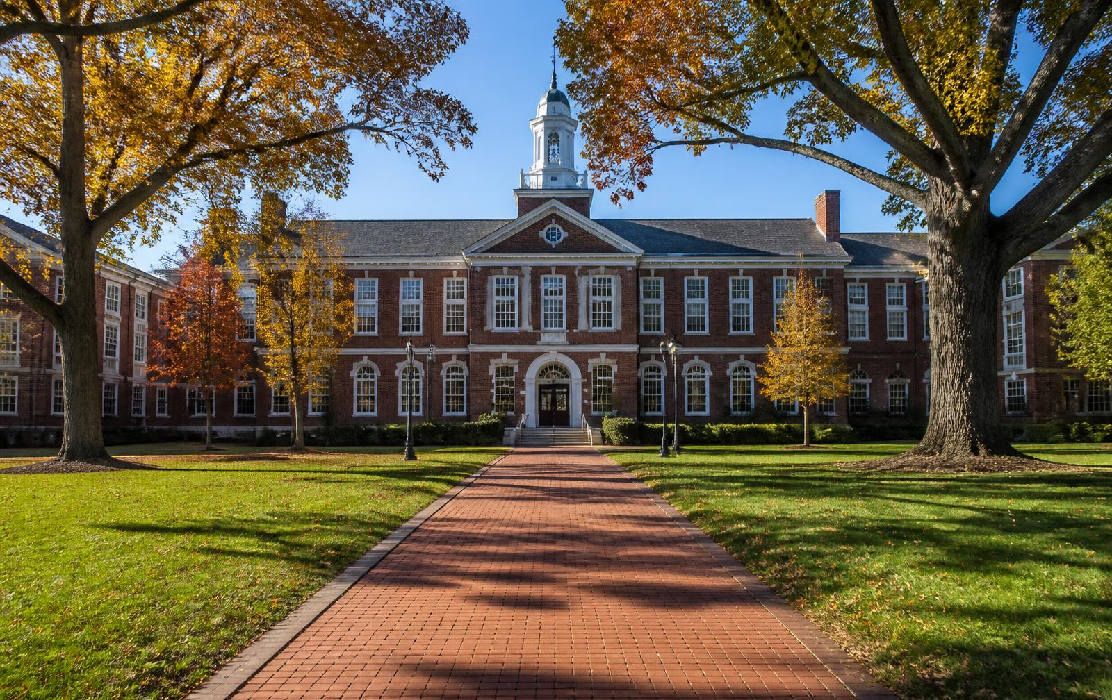 Brick school building with white cupola and oak-shaded brick walkway
