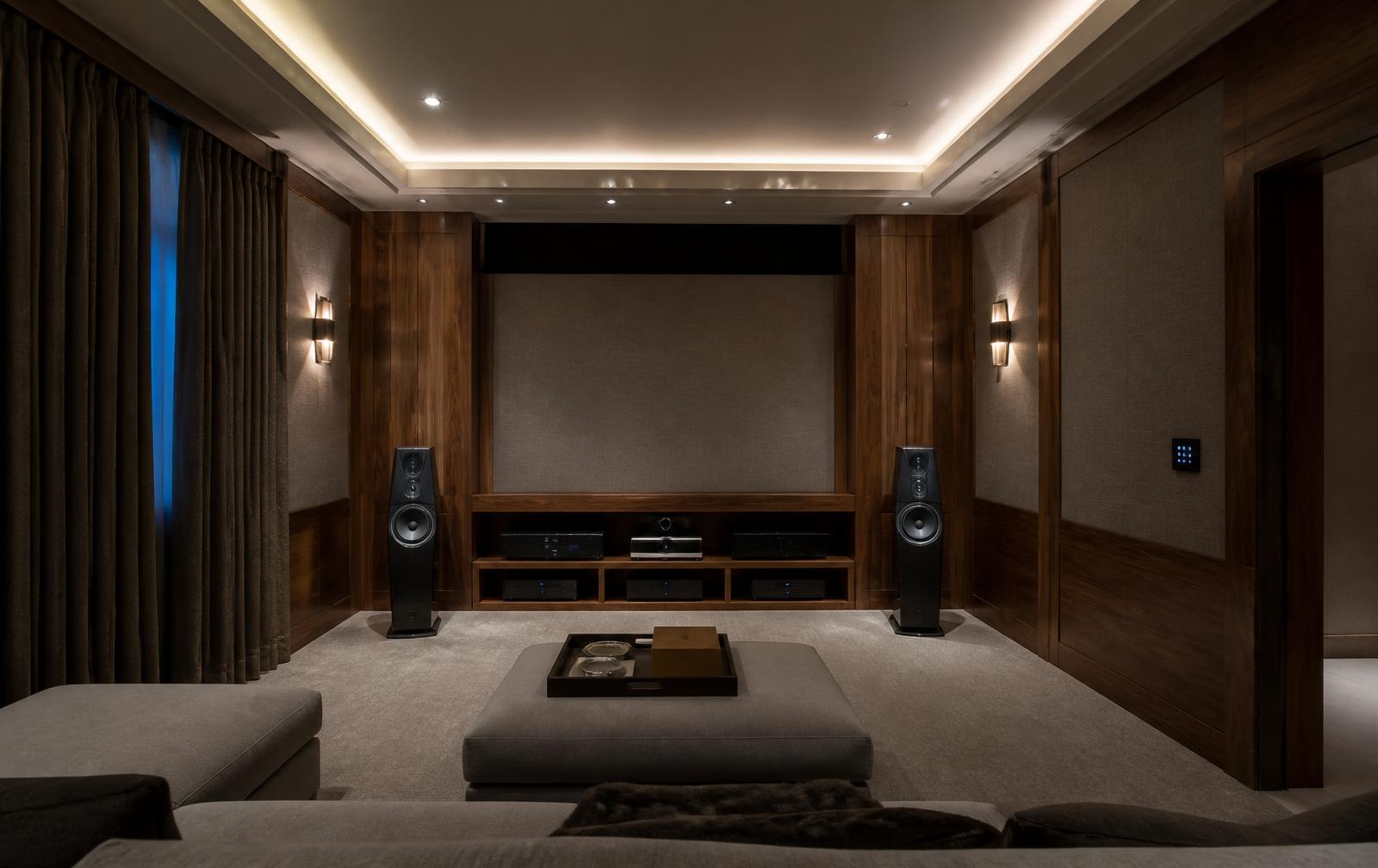 Walnut-paneled home media and listening room with concealed screen and wall keypad